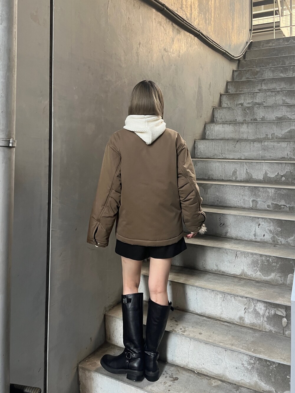 ブラウン系のブルゾン、ブラック系のブーツを着用したレディースの秋コーディネートの4枚目の写真