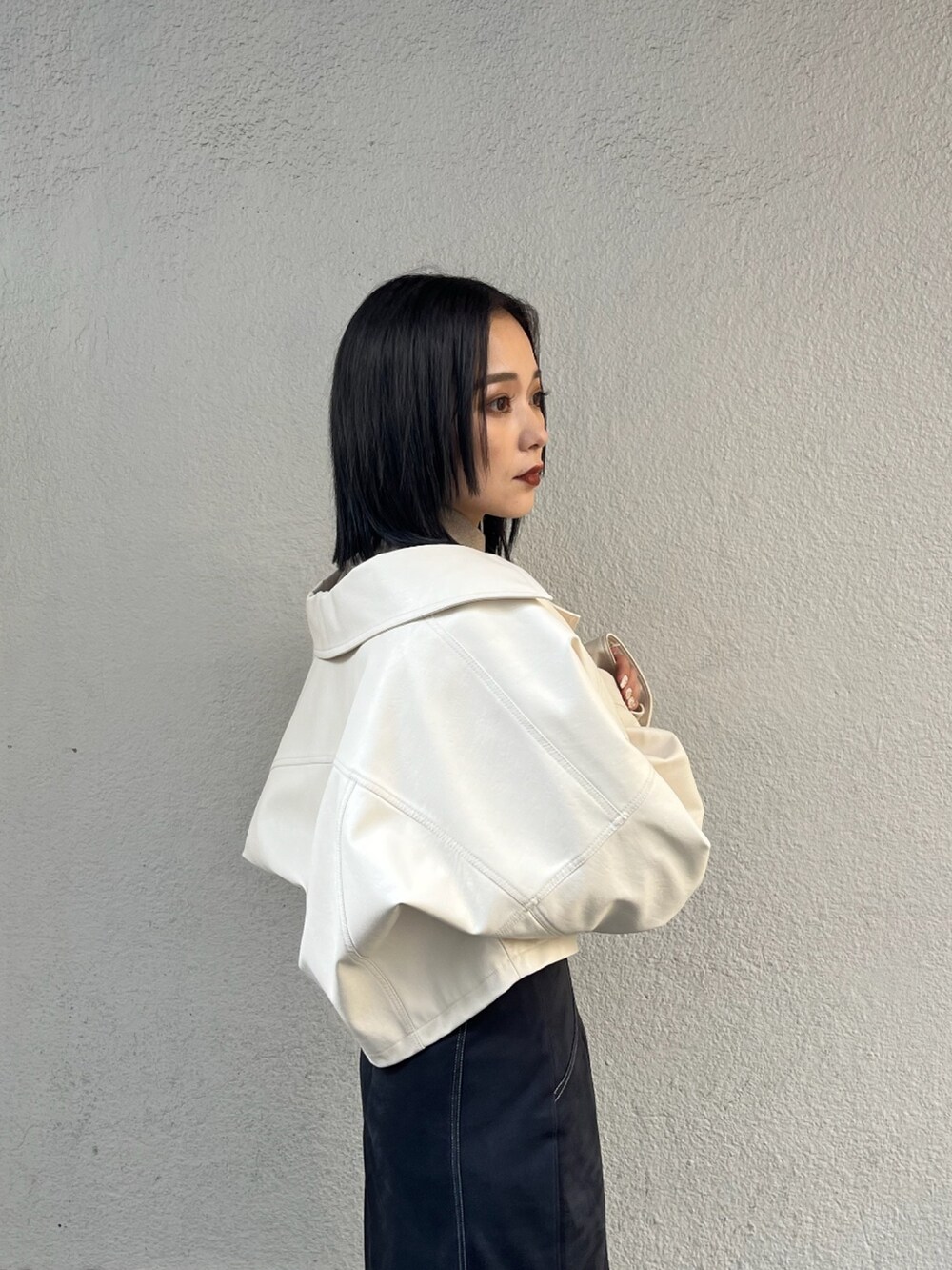 ベージュ系のニット/セーター、ホワイト系のブルゾン、ブラック系のブーツを着用したレディースの夏コーディネートの3枚目の写真