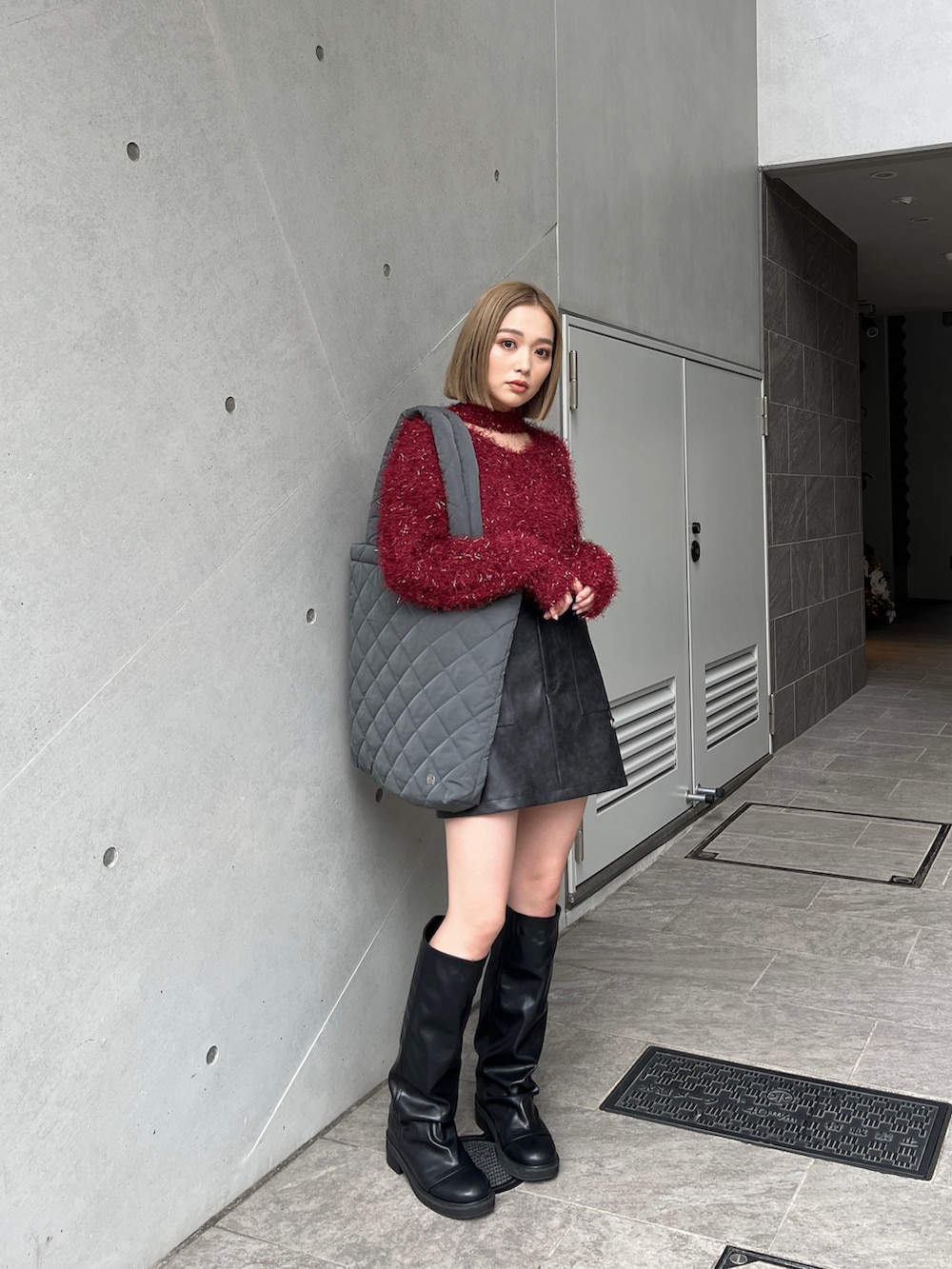 レッド系のニット/セーター、ブラウン系のスカート、ブラック系のブーツを着用したレディースの冬コーディネートの3枚目の写真