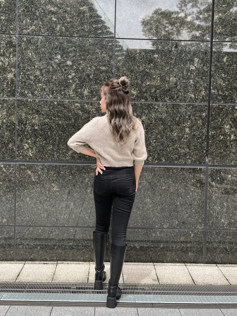 ブラック系のデニムパンツ、ブラック系のブーツ、ホワイト系のニット/セーターを着用したレディースの秋コーディネートの2枚目の写真