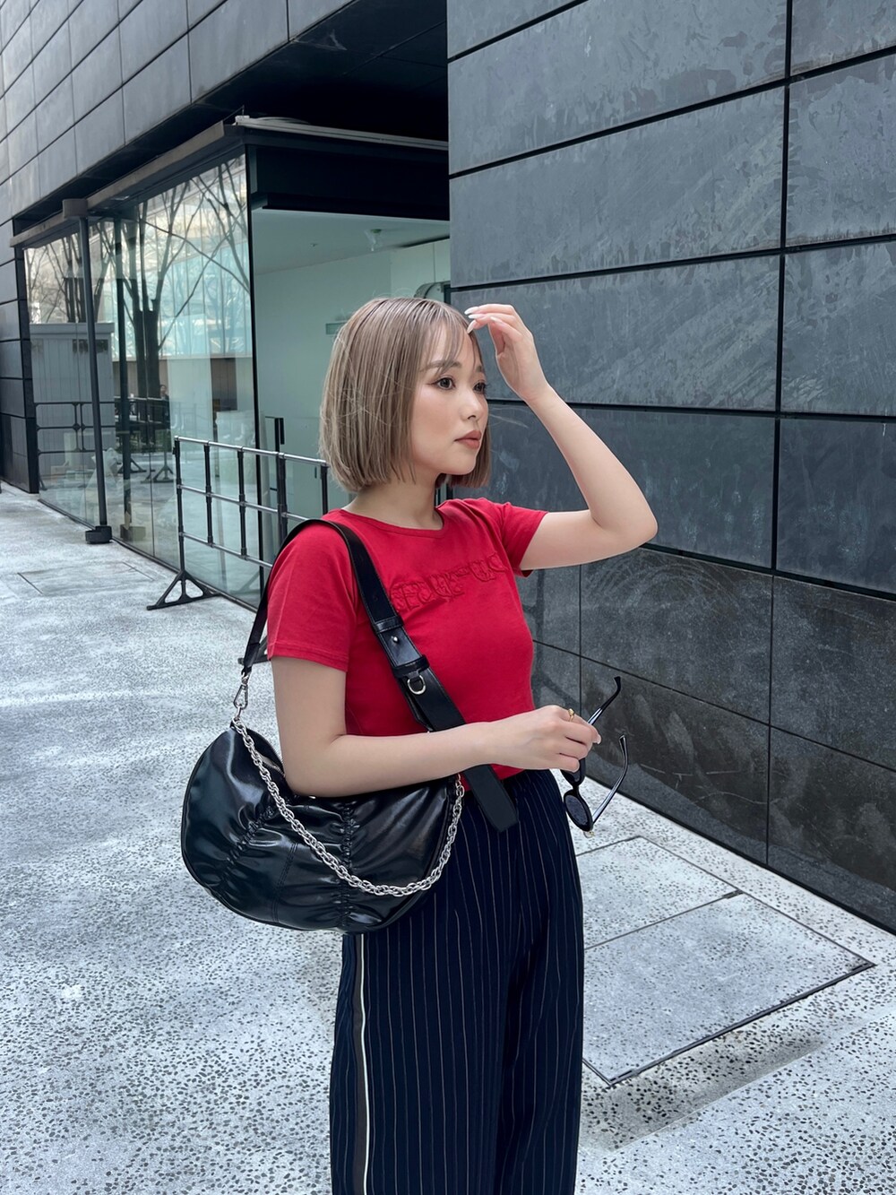 レッド系のTシャツ/カットソー、ブルー系のスラックス、ブラック系のショルダーバッグを着用したレディースの春コーディネートの4枚目の写真