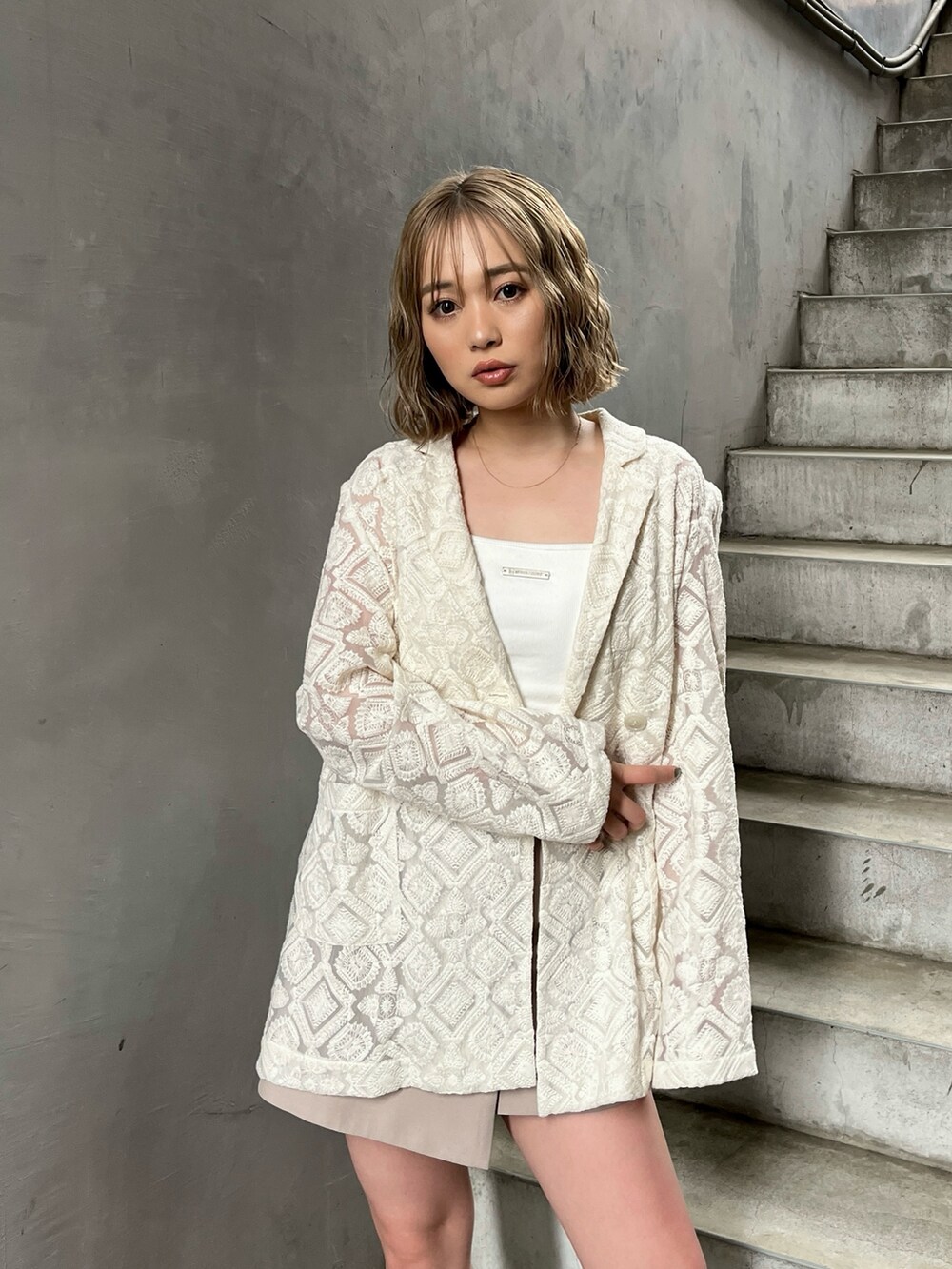 ホワイト系のテーラードジャケット、ホワイト系のキャミソール、ベージュ系のスカートを着用したレディースの春コーディネートの5枚目の写真