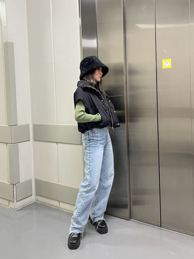 ブラック系のダウンベスト、グリーン系のニット/セーター、ブラック系のハットを着用したレディースの秋コーディネートの2枚目の写真