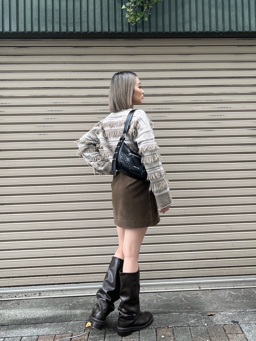 ホワイト系のニット/セーター、ブラック系のハンドバッグ、ブラウン系のスカートを着用したレディースの秋コーディネートの2枚目の写真