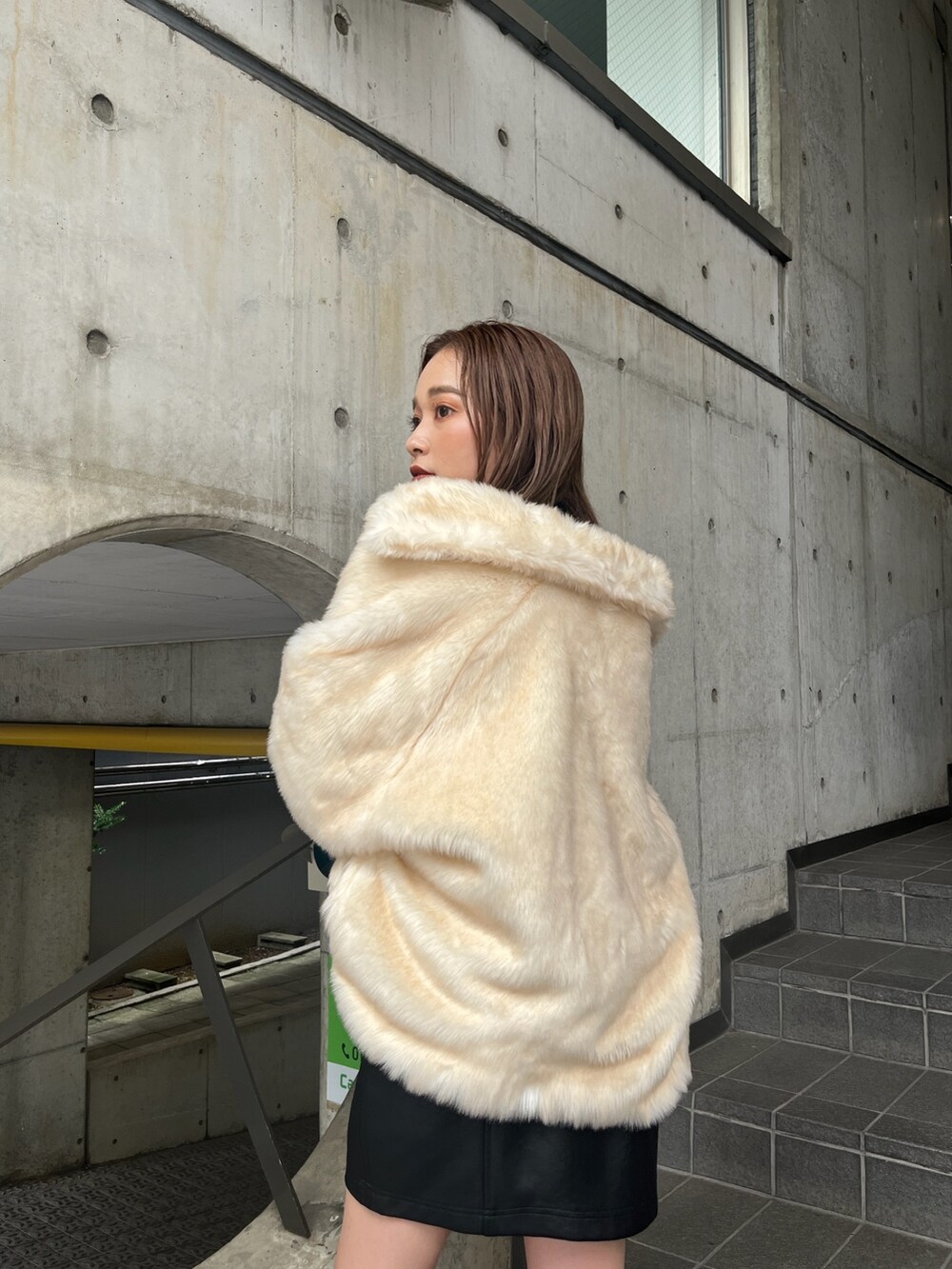 ホワイト系のブルゾン、ブルー系のニット/セーター、ブラック系のブーツを着用したレディースの秋コーディネートの4枚目の写真