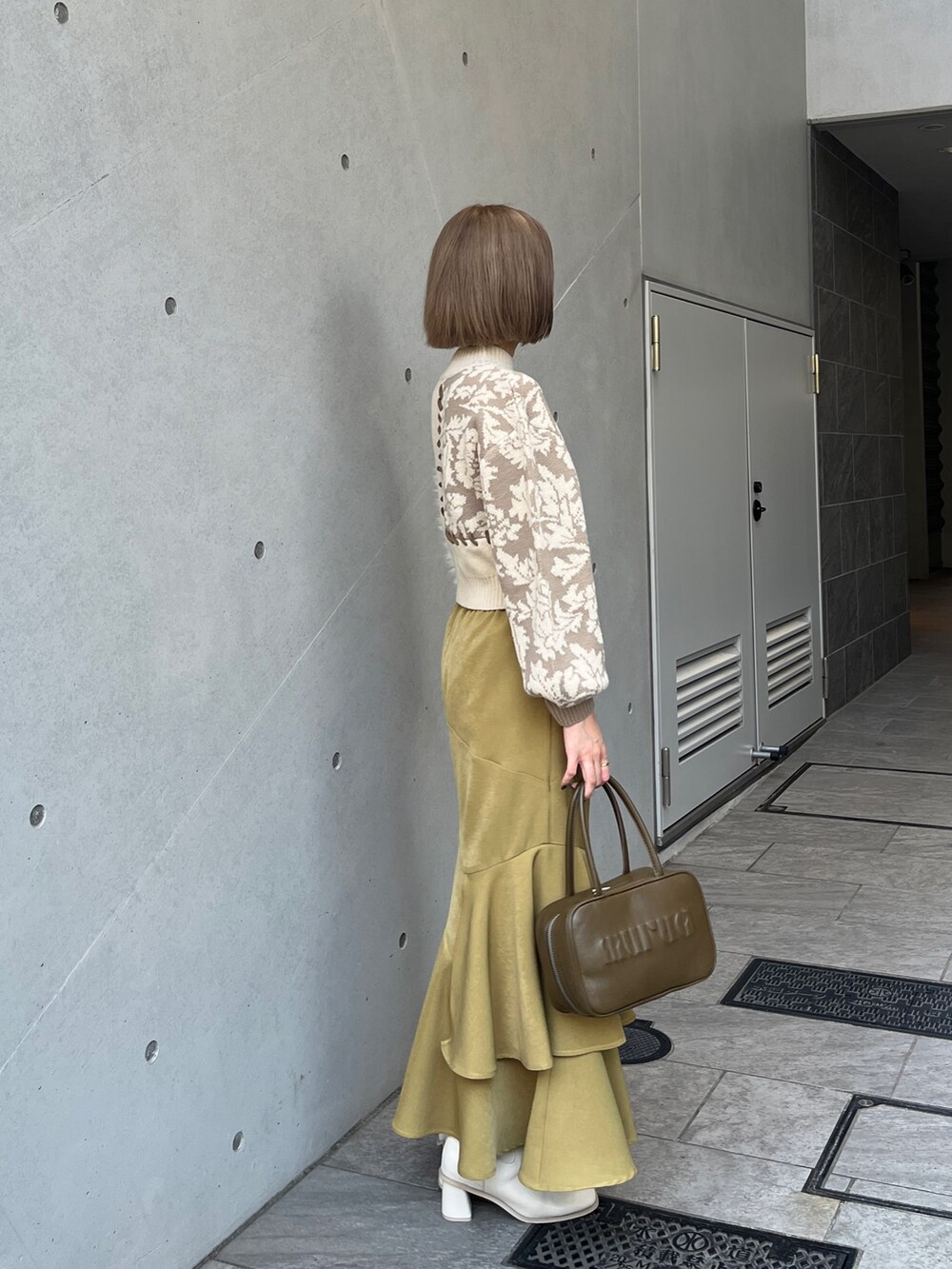 ホワイト系のニット/セーター、イエロー系のボストンバッグ、ホワイト系のブーツを着用したレディースの秋コーディネートの4枚目の写真