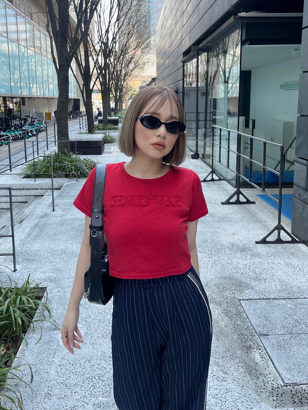 レッド系のTシャツ/カットソー、ブルー系のスラックス、ブラック系のショルダーバッグを着用したレディースの春コーディネートの5枚目の写真