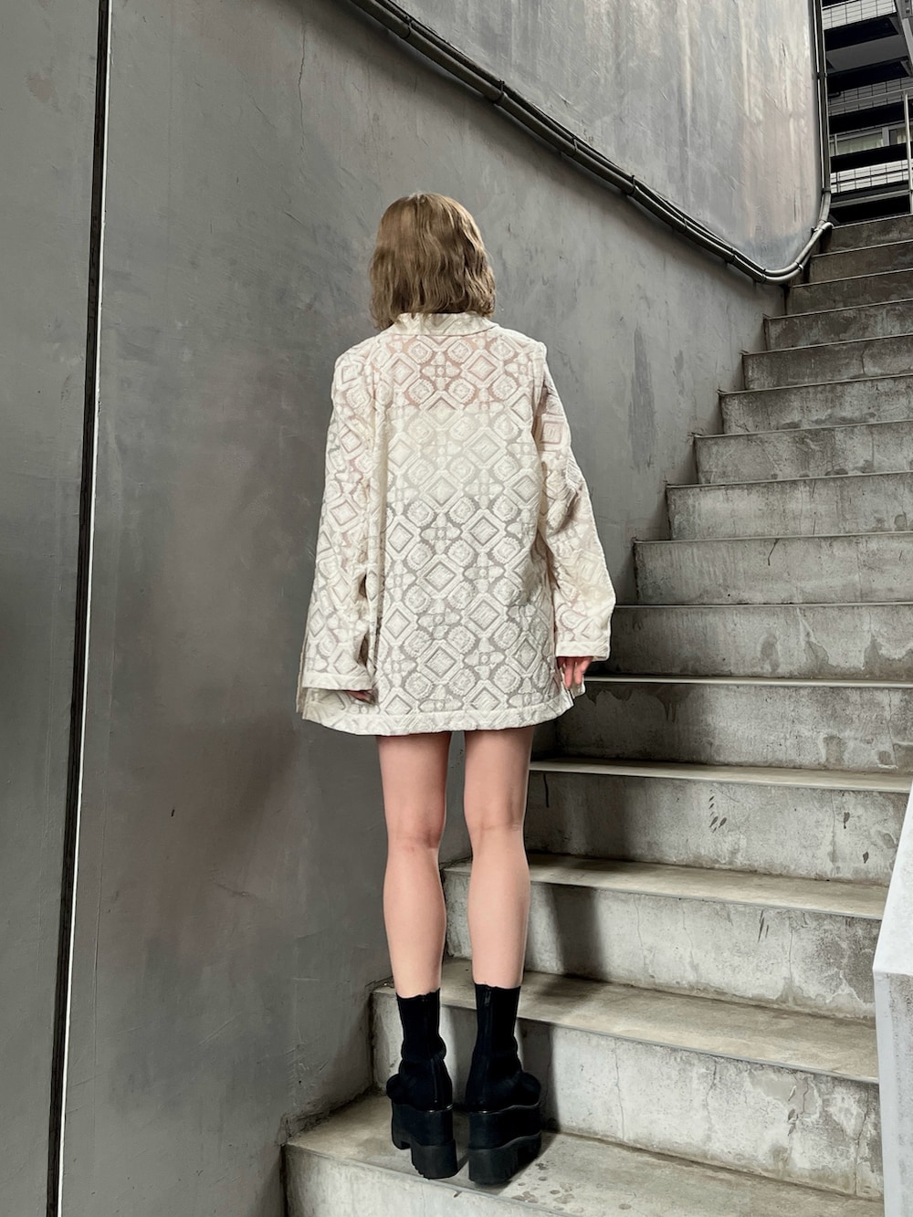 ホワイト系のテーラードジャケット、ホワイト系のキャミソール、ベージュ系のスカートを着用したレディースの春コーディネートの3枚目の写真