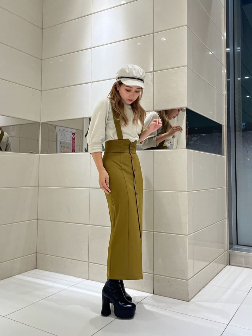 イエロー系のワンピース、ブラック系のブーツ、ホワイト系のニット/セーターを着用したレディースの秋コーディネートの2枚目の写真