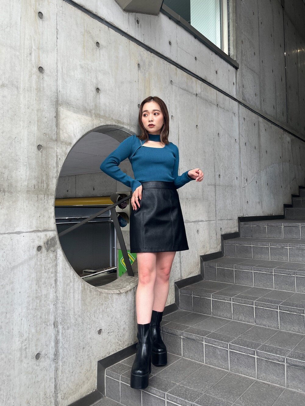 ホワイト系のブルゾン、ブルー系のニット/セーター、ブラック系のブーツを着用したレディースの秋コーディネートの5枚目の写真