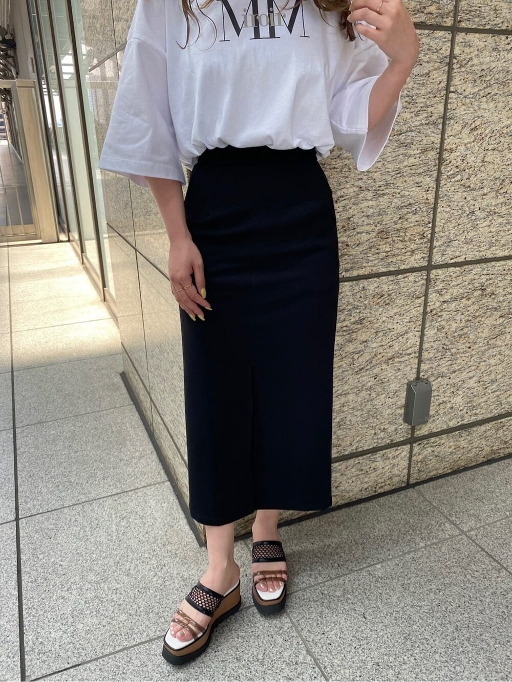 ブラック系のスカート、ホワイト系のTシャツ/カットソー、その他のサンダルを着用したレディースの春コーディネートの7枚目の写真