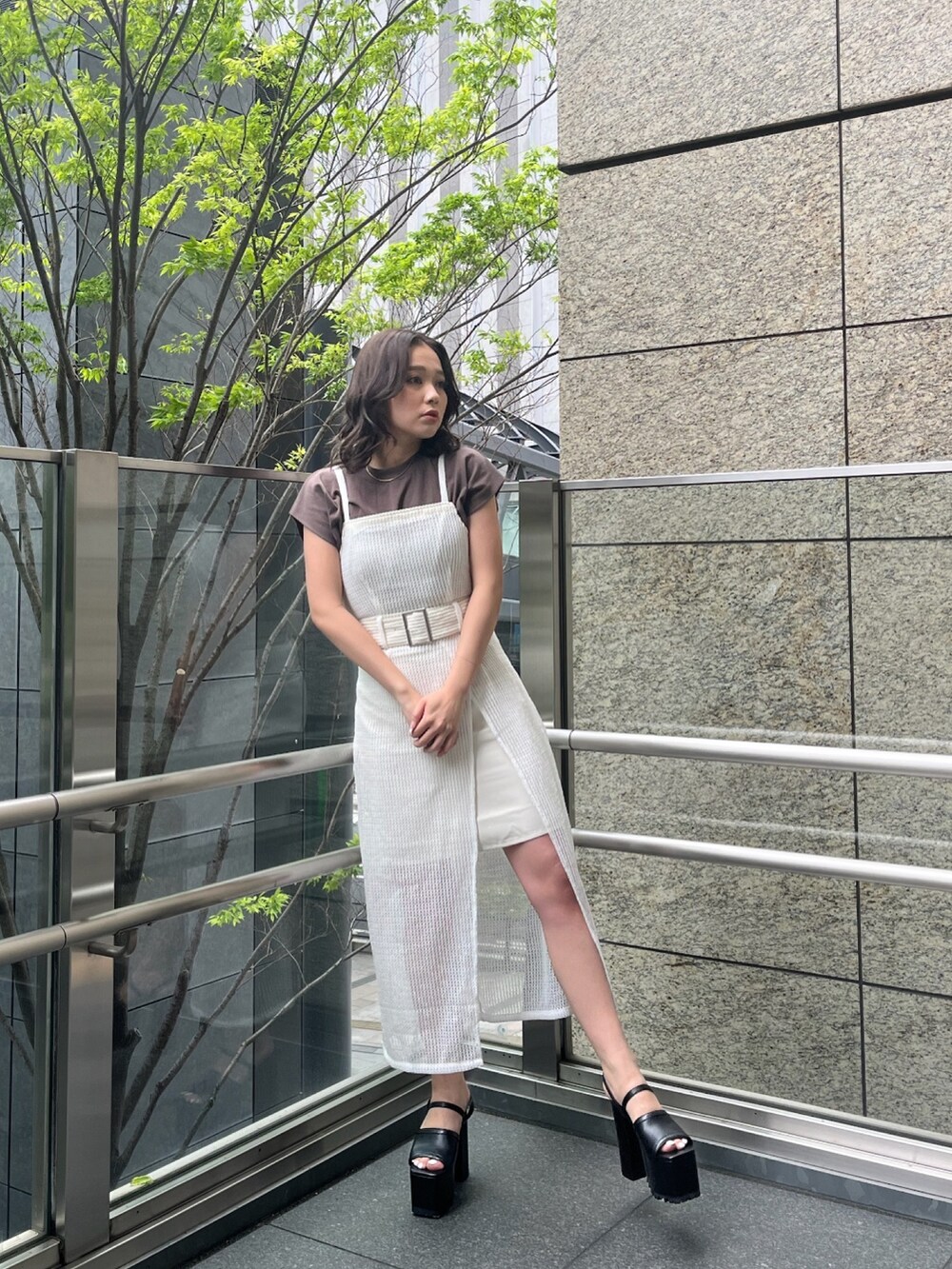 ホワイト系のワンピース、ブラウン系のTシャツ/カットソー、ブラック系のサンダルを着用したレディースの春コーディネートの2枚目の写真