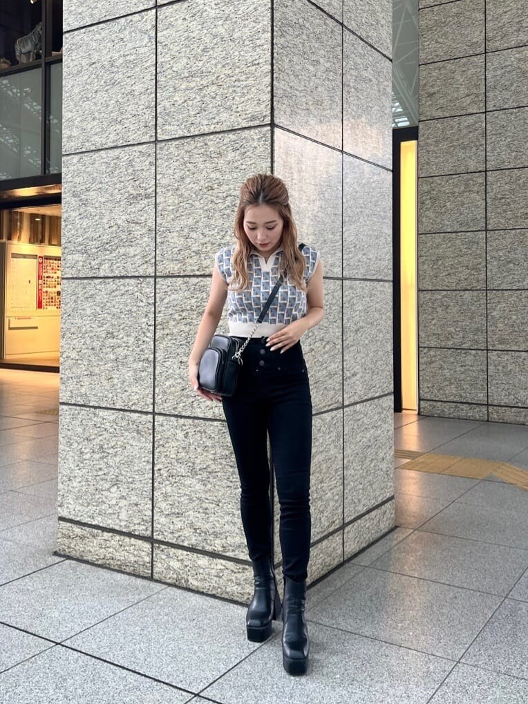 ブラック系のデニムパンツ、ブラック系のショルダーバッグ、ホワイト系のニット/セーターを着用したレディースの夏コーディネートの4枚目の写真