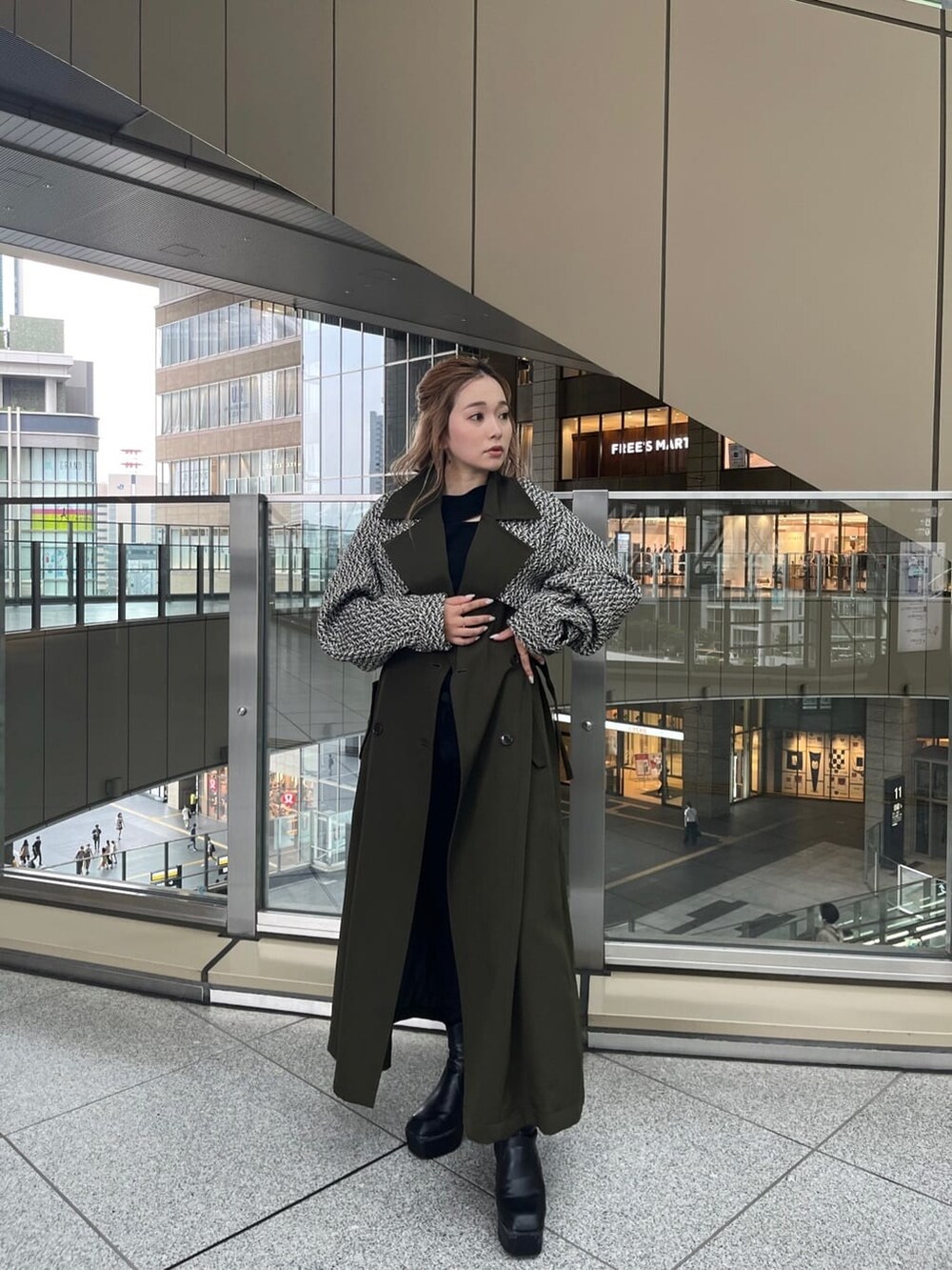 ブラック系のデニムパンツ、ブラック系のニット/セーター、ベージュ系のトレンチコートを着用したレディースの夏コーディネートの2枚目の写真