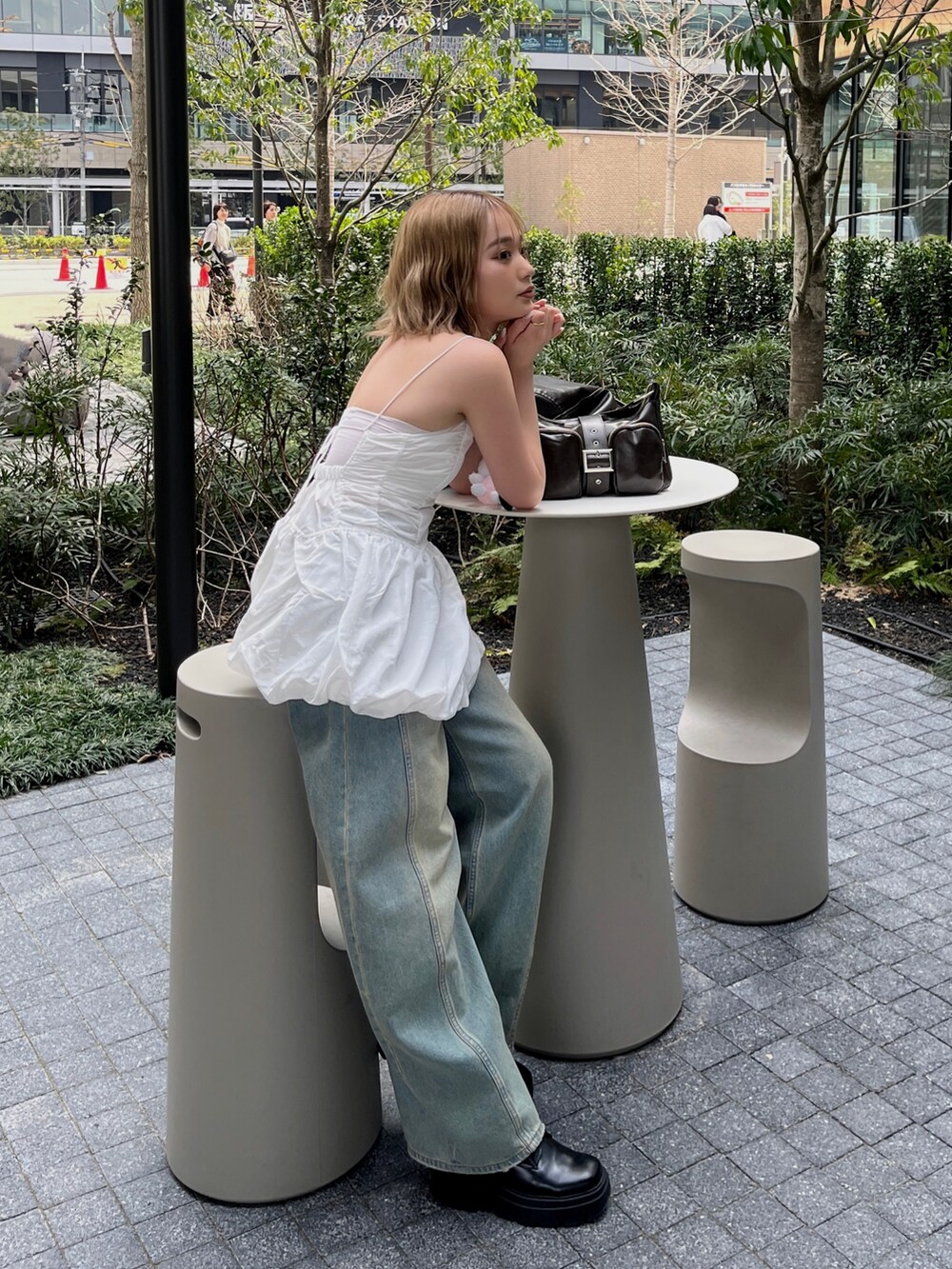 ホワイト系のキャミソール、ブルー系のデニムパンツ、ブラウン系のハンドバッグを着用したレディースの春コーディネートの2枚目の写真