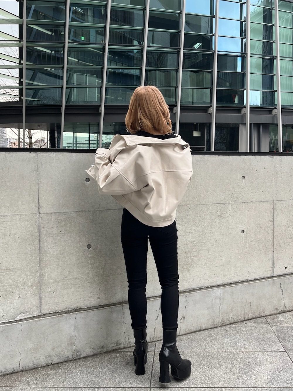 ホワイト系のブルゾン、ブラック系のニット/セーター、ブラック系のデニムパンツを着用したレディースの冬コーディネートの3枚目の写真