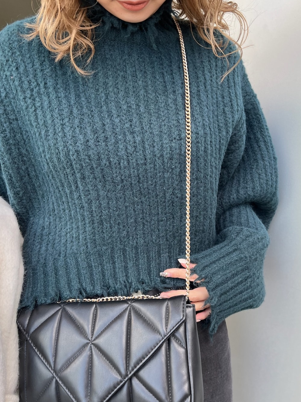 ホワイト系のチェスターコート、グリーン系のニット/セーター、ブラック系のブーツを着用したレディースの冬コーディネートの9枚目の写真