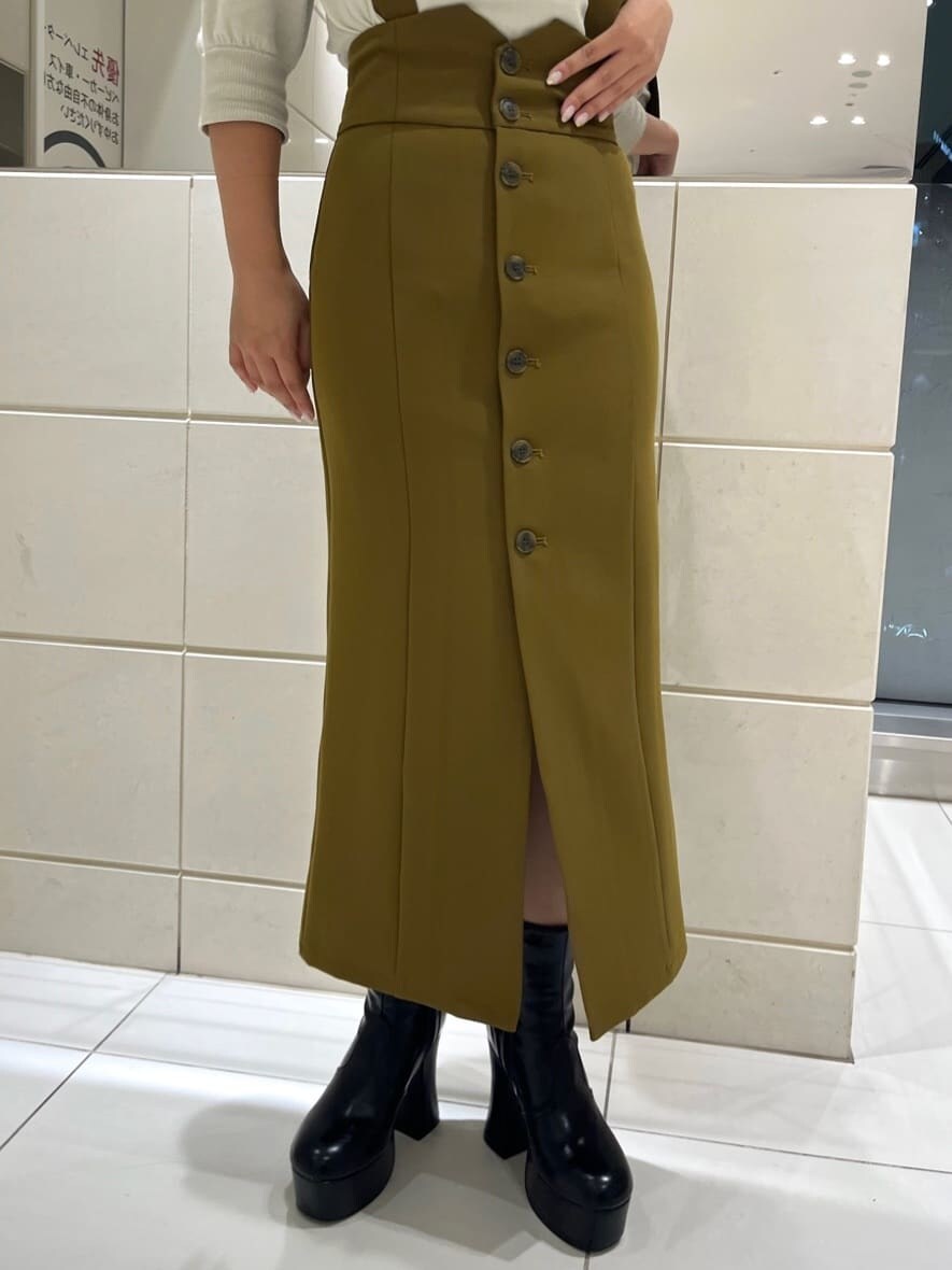 イエロー系のワンピース、ブラック系のブーツ、ホワイト系のニット/セーターを着用したレディースの秋コーディネートの8枚目の写真