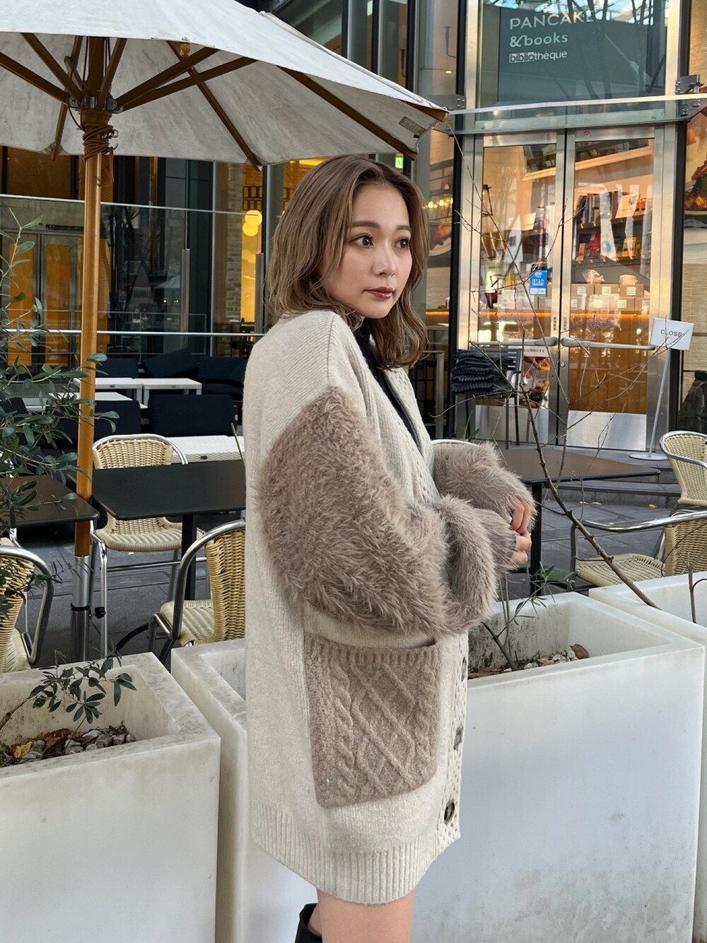 ベージュ系のカーディガン/ボレロ、ブラック系のニット/セーター、ブラック系のブーツを着用したレディースの秋コーディネートの6枚目の写真