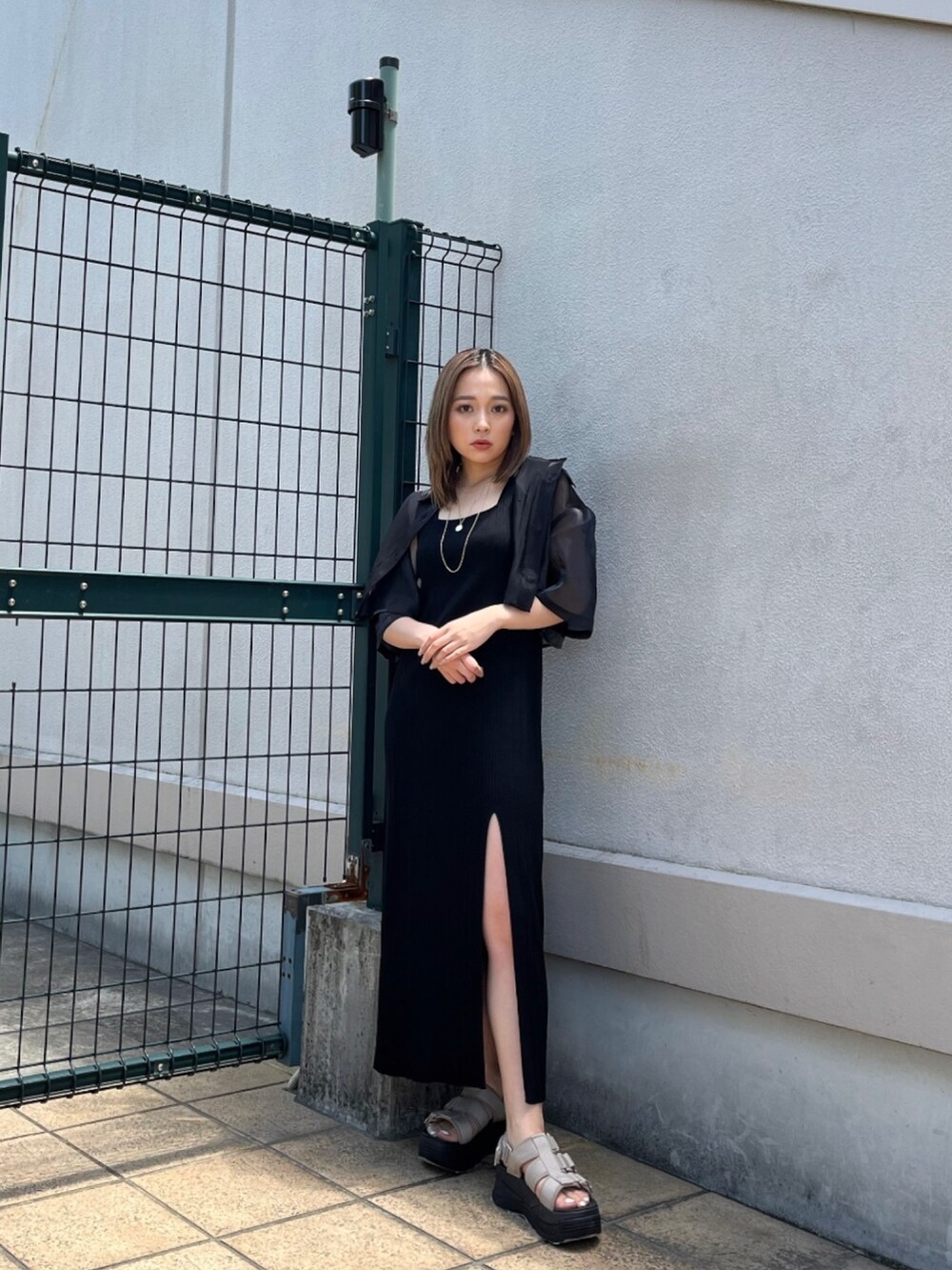 ブラック系のシャツ/ブラウス、ブラック系のワンピース、ブラウン系のサンダルを着用したレディースの春コーディネートの2枚目の写真