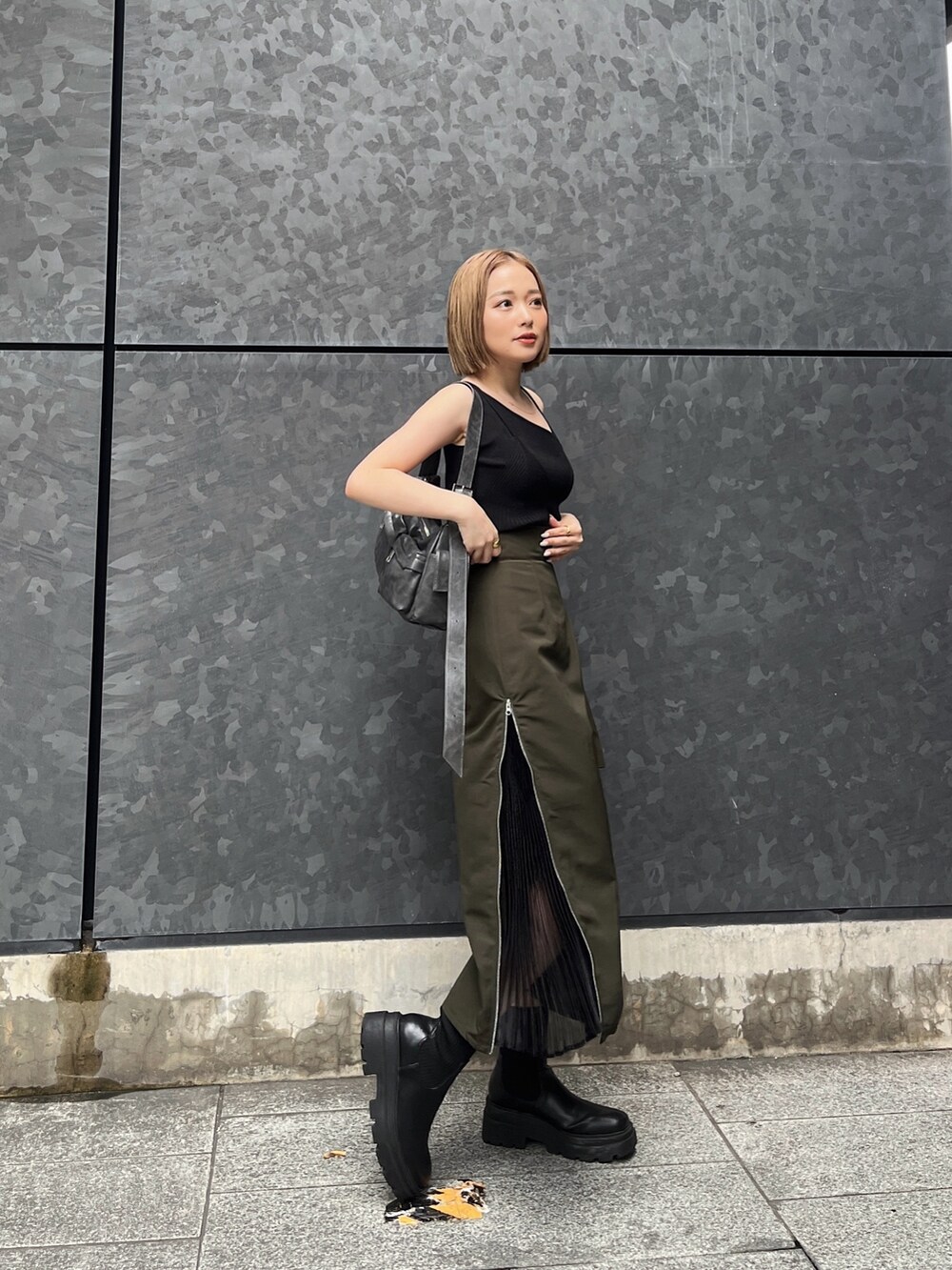 ブラック系のニット/セーター、グリーン系のスカート、グレー系のショルダーバッグを着用したレディースの夏コーディネートの3枚目の写真