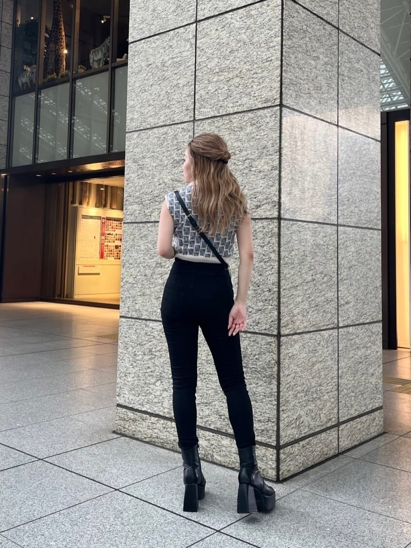 ブラック系のデニムパンツ、ブラック系のショルダーバッグ、ホワイト系のニット/セーターを着用したレディースの夏コーディネートの3枚目の写真