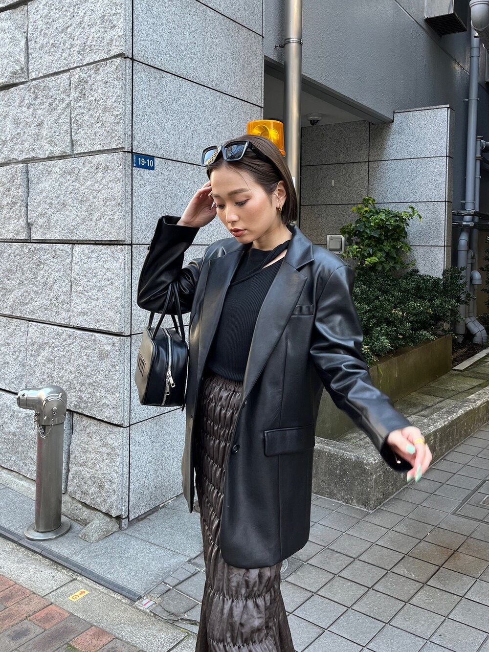 ブラック系のテーラードジャケット、ブラック系のニット/セーター、ブラウン系のスカートを着用したレディースの春コーディネートの4枚目の写真