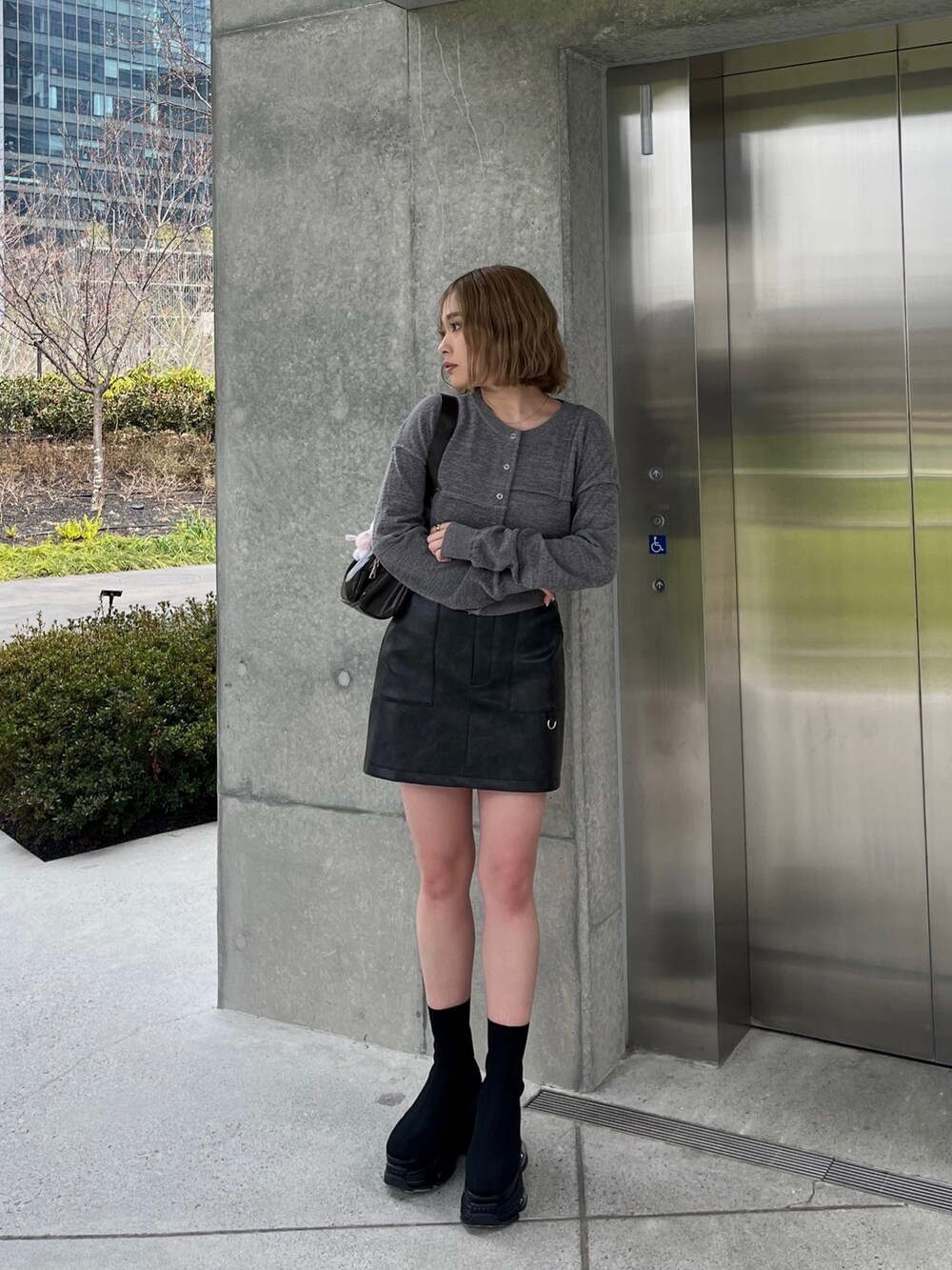ブラック系のブーツ、ブラック系のスカート、グレー系のカーディガン/ボレロを着用したレディースの春コーディネートの2枚目の写真