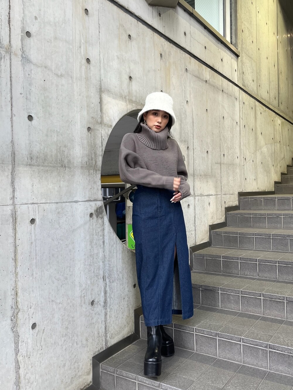 ブラウン系のニット/セーター、ブルー系のスカート、ブラック系のブーツを着用したレディースの夏コーディネートの2枚目の写真