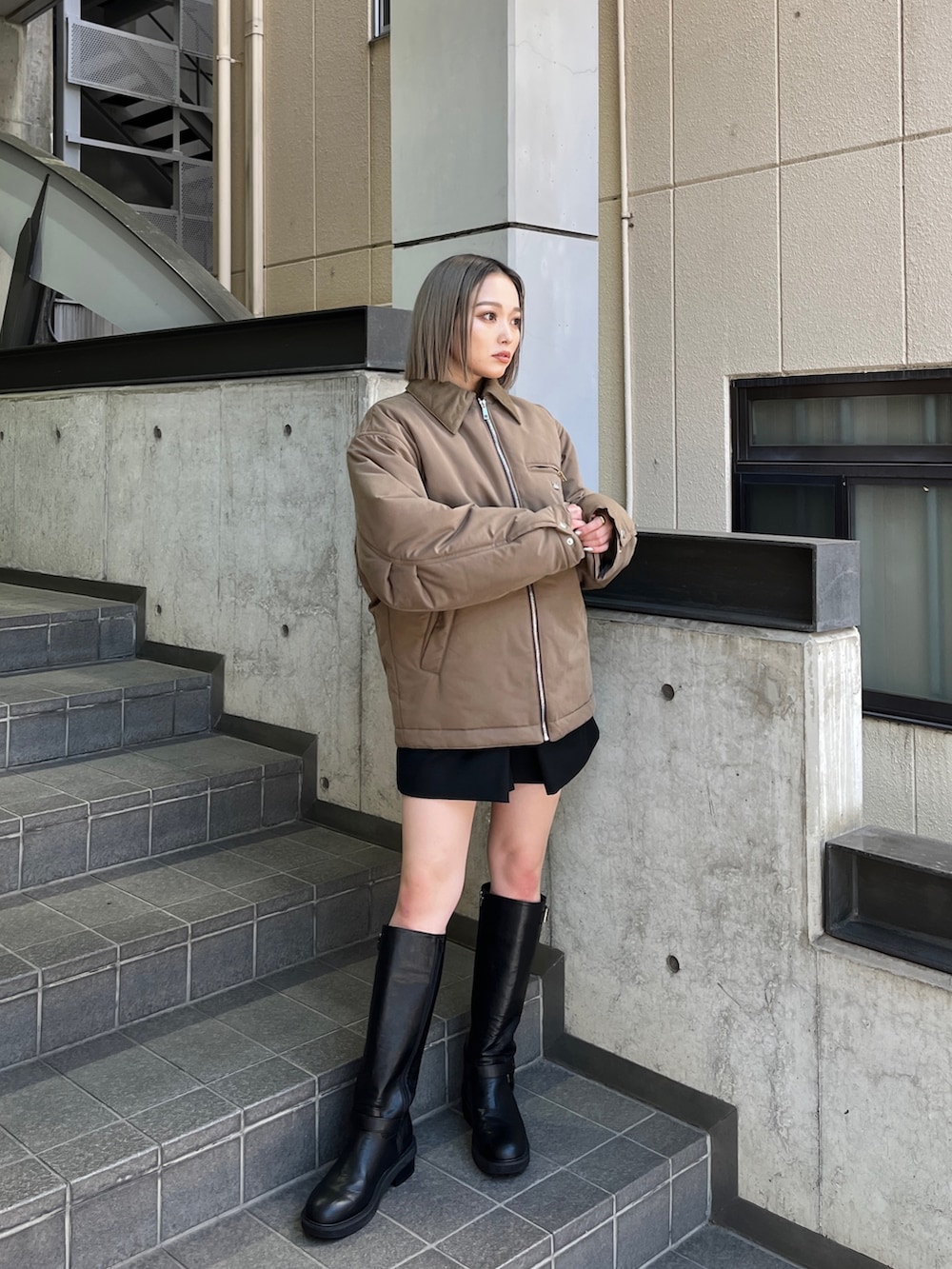 ブラウン系のブルゾン、ブラック系のブーツを着用したレディースの秋コーディネートの2枚目の写真