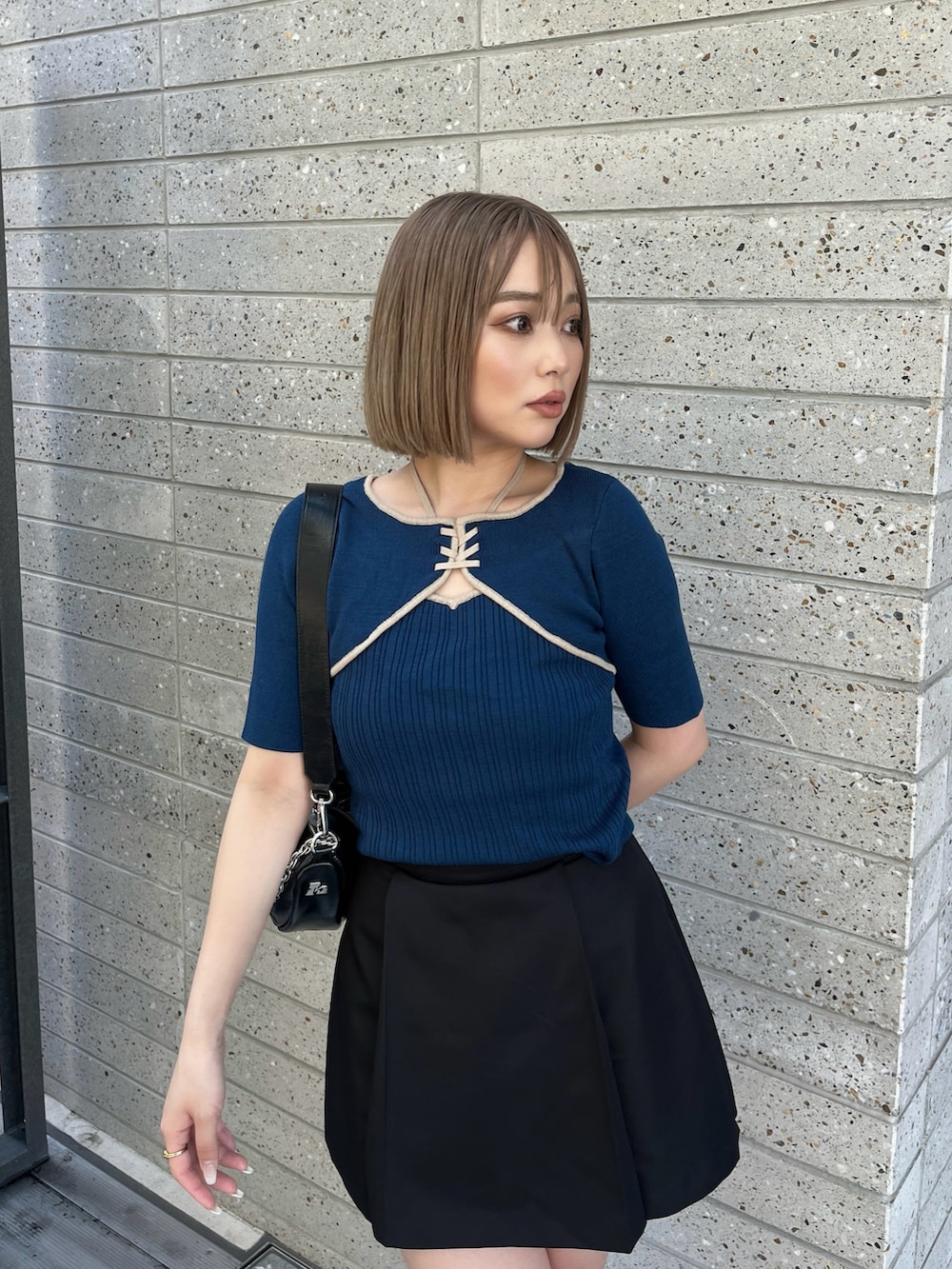 ブラック系のブーツ、ブラック系のスカート、ブルー系のニット/セーターを着用したレディースの春コーディネートの6枚目の写真