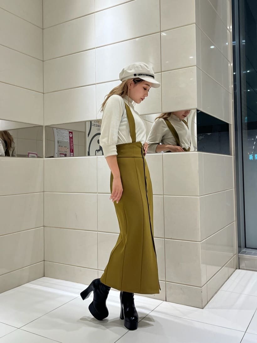 イエロー系のワンピース、ブラック系のブーツ、ホワイト系のニット/セーターを着用したレディースの秋コーディネートの4枚目の写真