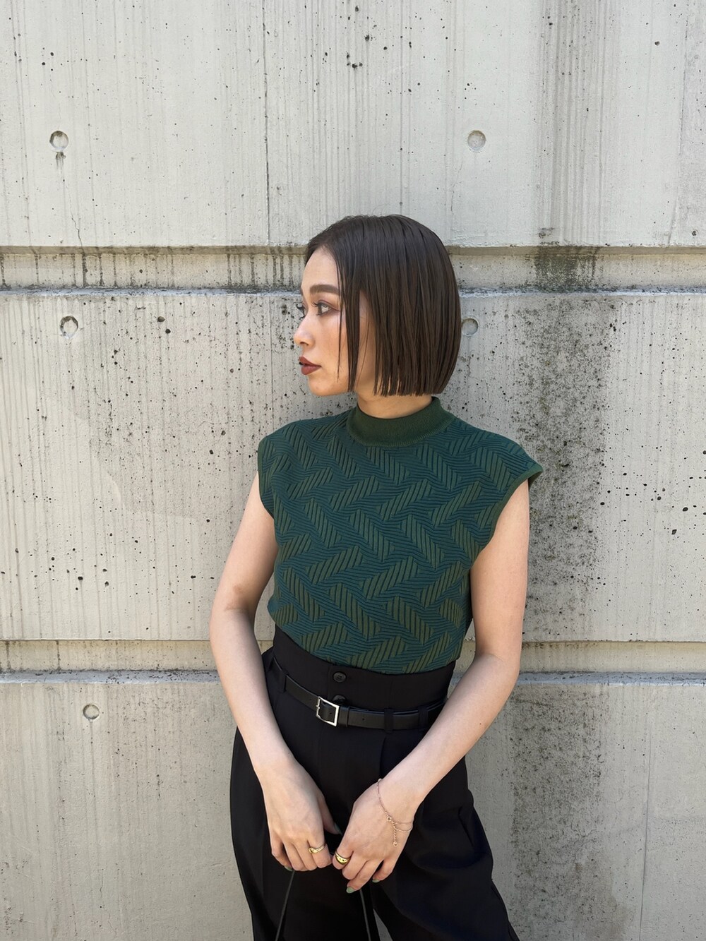 グリーン系のニット/セーター、ブラック系のその他パンツ、ブラック系のブーツを着用したレディースの夏コーディネートの8枚目の写真