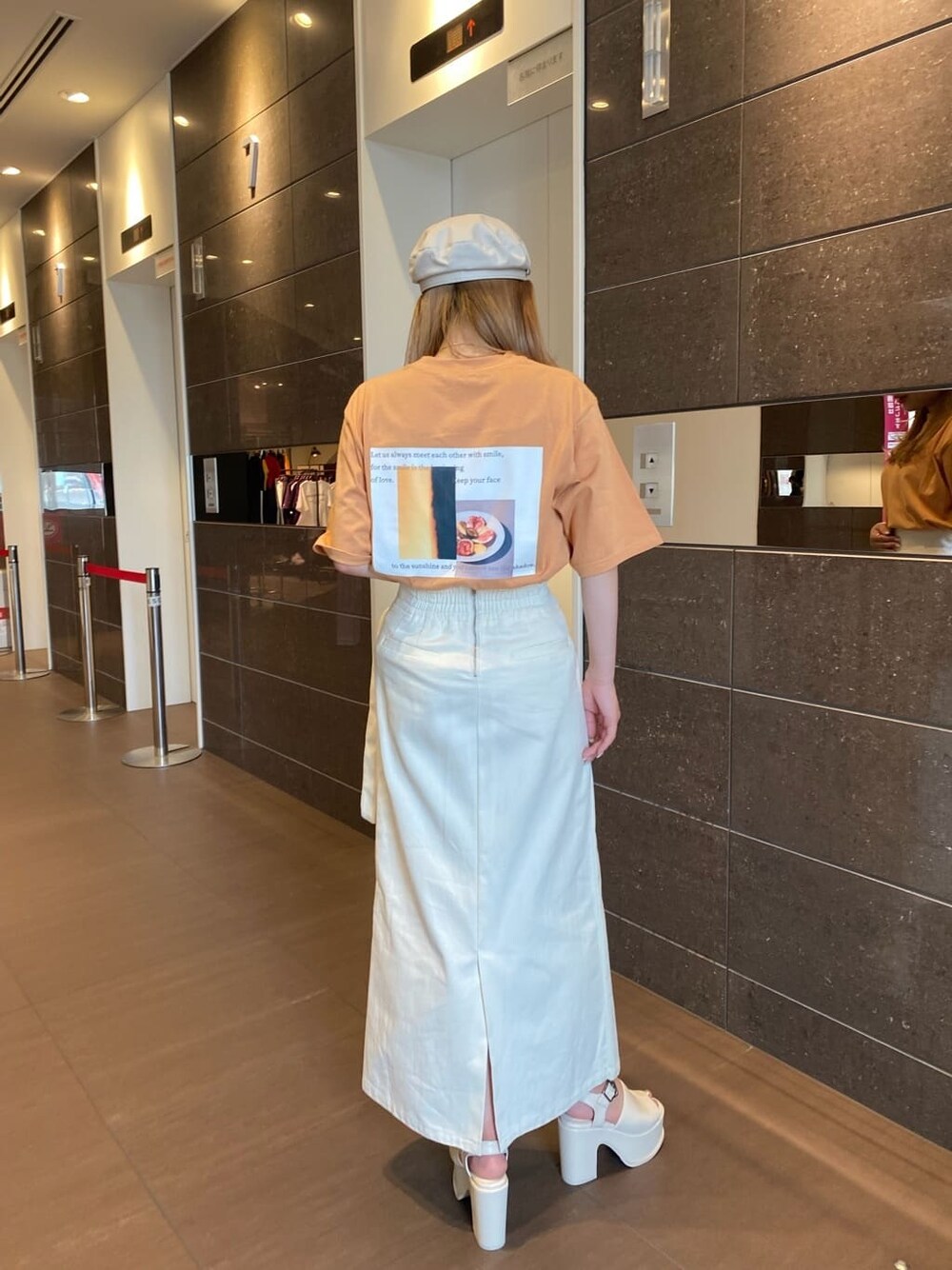 ホワイト系のスカート、オレンジ系のTシャツ/カットソー、ホワイト系のサンダルを着用したレディースの春コーディネートの4枚目の写真