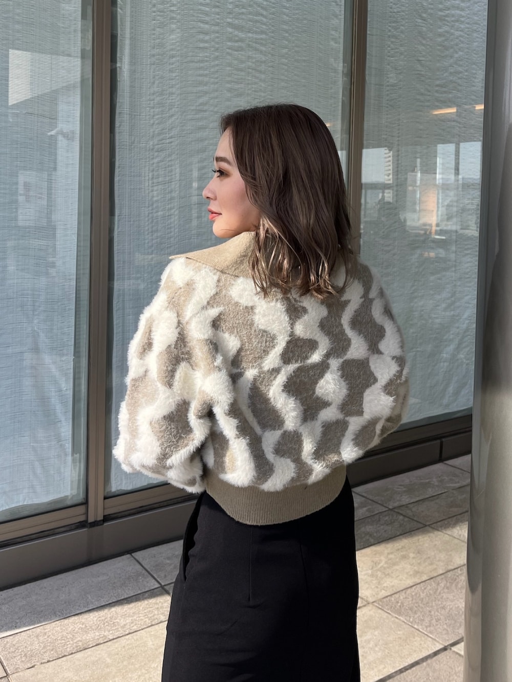 ベージュ系のニット/セーター、ブラック系のスカート、ブラック系のブーツを着用したレディースの秋コーディネートの6枚目の写真