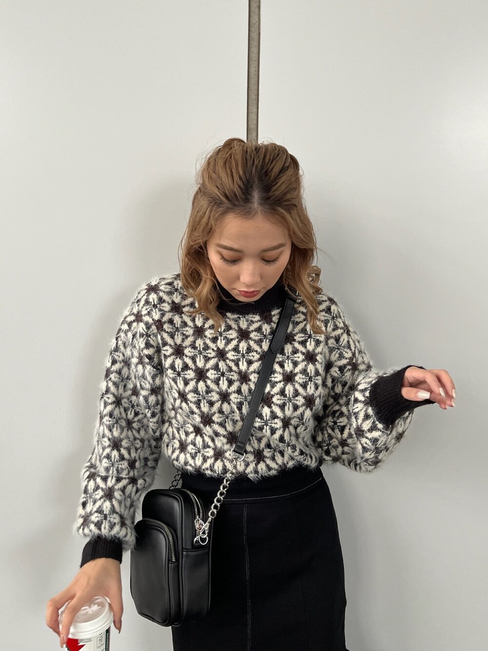 ブラック系のニット/セーター、ブラック系のスカート、ブラック系のショルダーバッグを着用したレディースの秋コーディネートの4枚目の写真