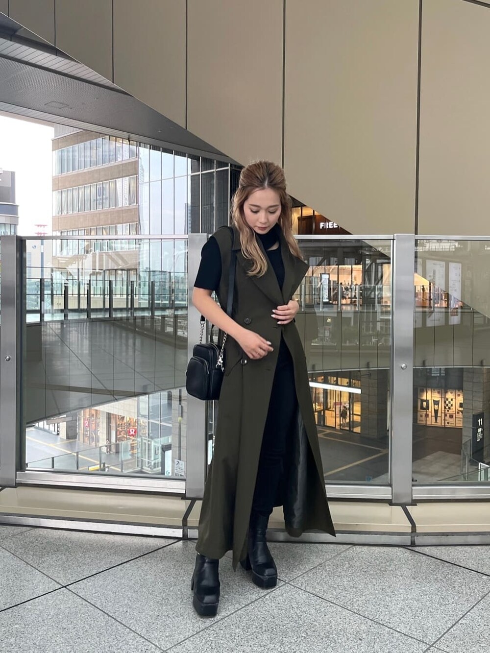 ブラック系のデニムパンツ、ブラック系のニット/セーター、ベージュ系のトレンチコートを着用したレディースの夏コーディネートの4枚目の写真