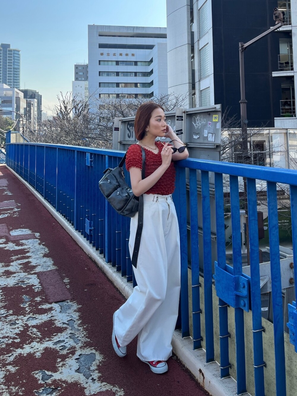 ホワイト系のデニムパンツ、ブラック系のショルダーバッグ、レッド系のシャツ/ブラウスを着用したレディースの春コーディネートの2枚目の写真