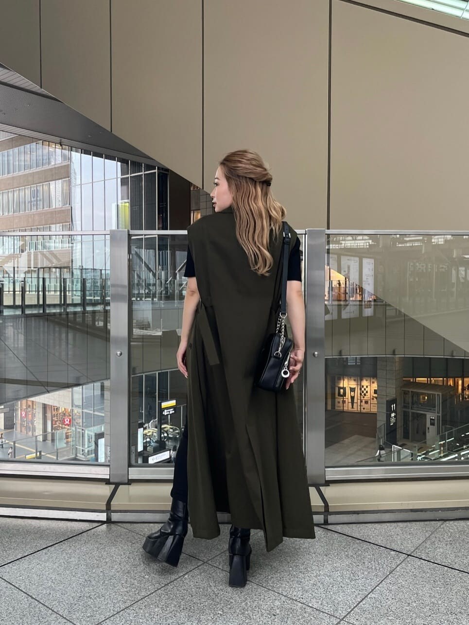 ブラック系のデニムパンツ、ブラック系のニット/セーター、ベージュ系のトレンチコートを着用したレディースの夏コーディネートの5枚目の写真