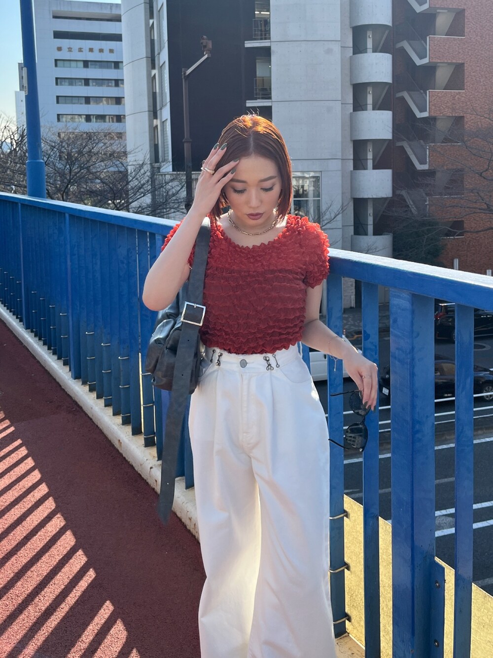 ホワイト系のデニムパンツ、ブラック系のショルダーバッグ、レッド系のシャツ/ブラウスを着用したレディースの春コーディネートの4枚目の写真