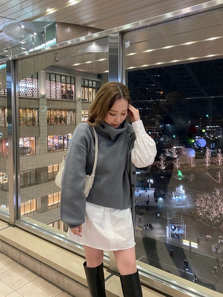 ホワイト系のハンドバッグ、ブラック系のブーツ、ブルー系のワンピースを着用したレディースの冬コーディネートの2枚目の写真