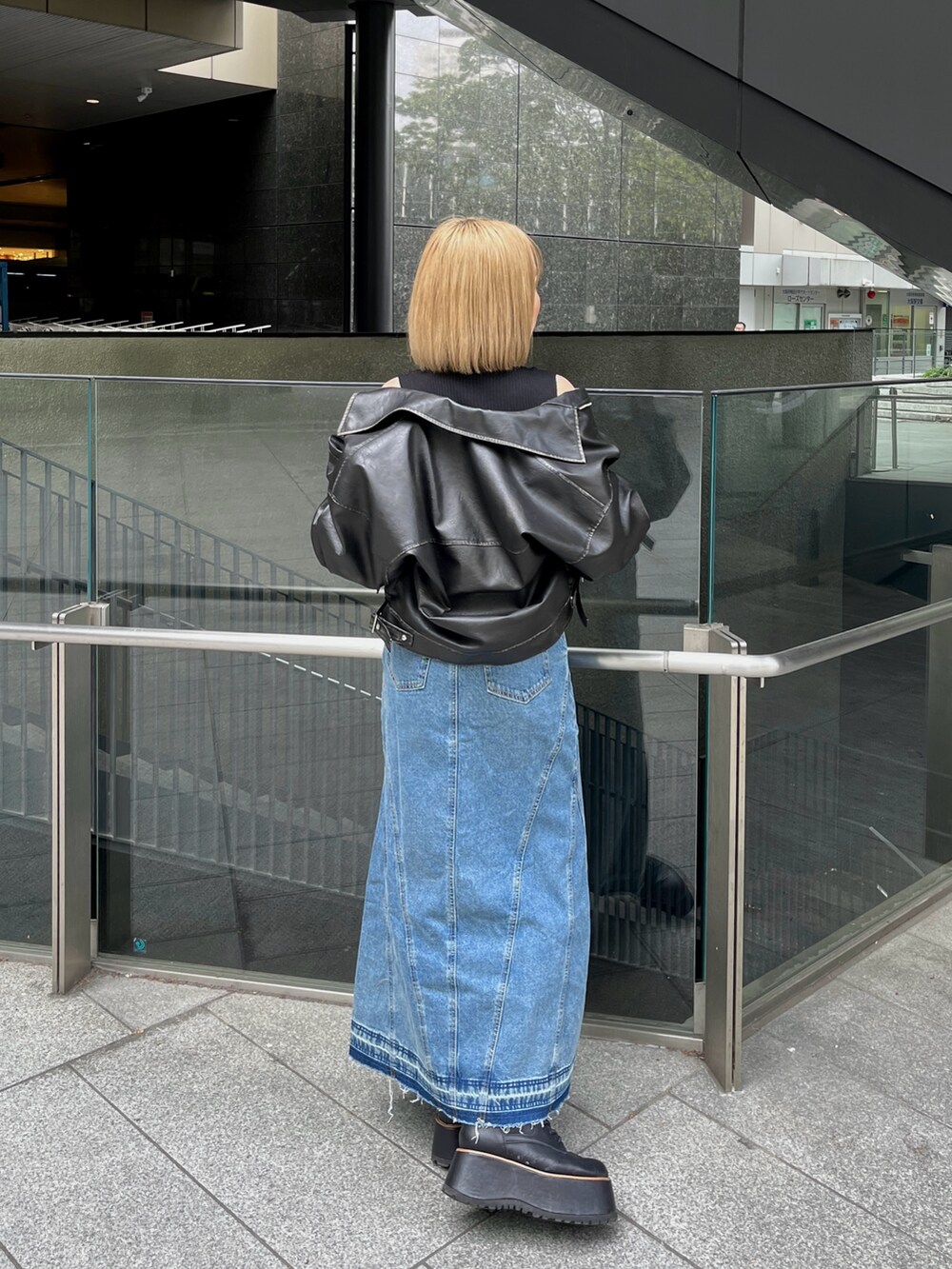 ブラック系のブーツ、ブルー系のデニムスカート、ブラック系のニット/セーターを着用したレディースの春コーディネートの4枚目の写真