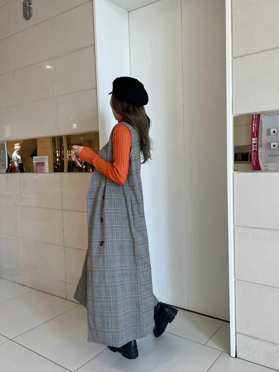 ブラック系のブーツ、オレンジ系のニット/セーター、ゴールド系のネックレスを着用したレディースの秋コーディネートの2枚目の写真