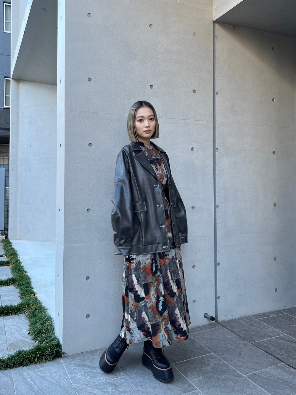 グレー系のブルゾン、ブラウン系のワンピース、ブラック系のブーツを着用したレディースの秋コーディネートの2枚目の写真