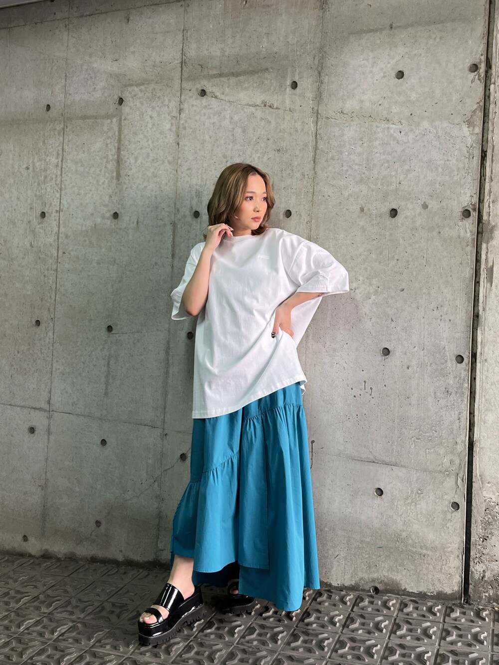 ブルー系のワンピース、ブラック系のサンダル、ホワイト系のTシャツ/カットソーを着用したレディースの春コーディネートの2枚目の写真