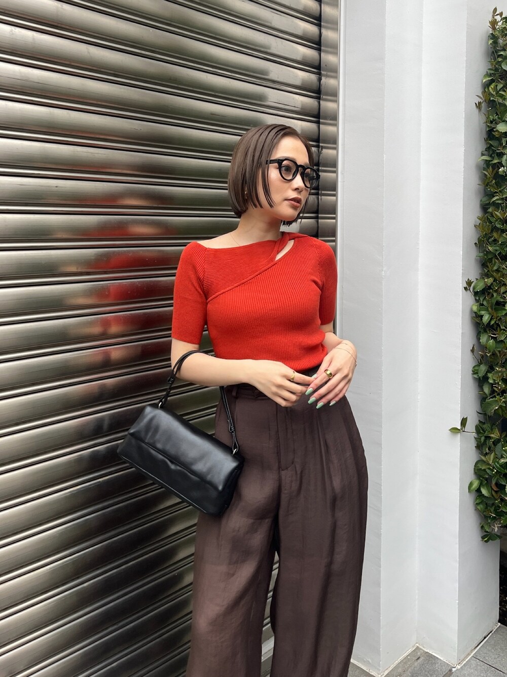 オレンジ系のニット/セーター、ブラウン系のその他パンツ、ブラック系のサンダルを着用したレディースの夏コーディネートの4枚目の写真