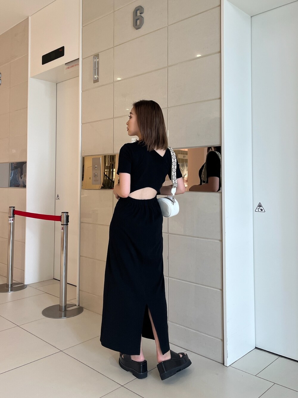 ブラック系のワンピース、ホワイト系のショルダーバッグ、ブラック系のサンダルを着用したレディースの夏コーディネートの2枚目の写真