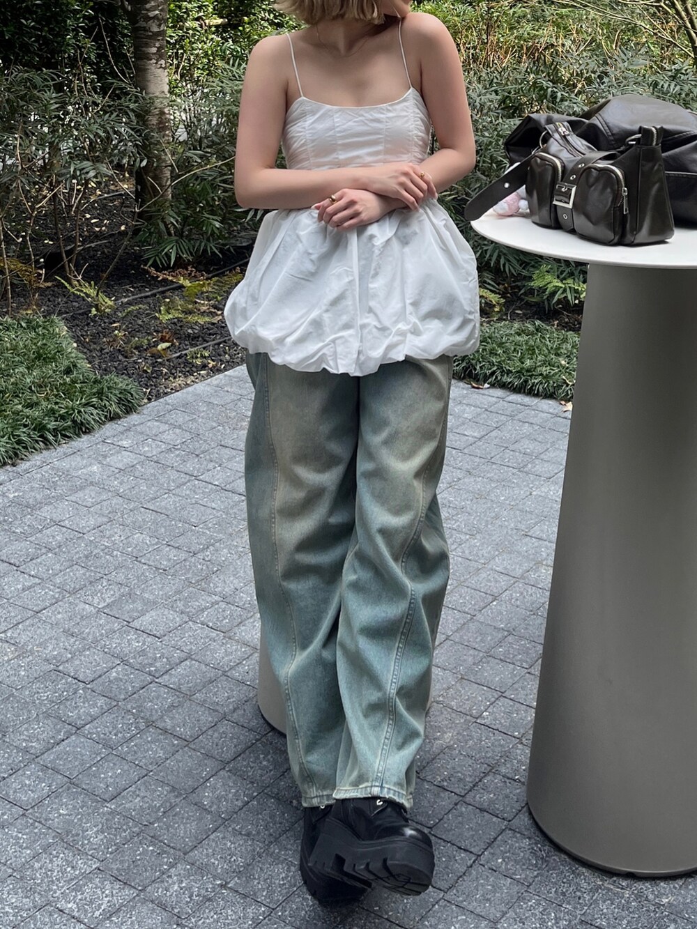 ホワイト系のキャミソール、ブルー系のデニムパンツ、ブラウン系のハンドバッグを着用したレディースの春コーディネートの4枚目の写真