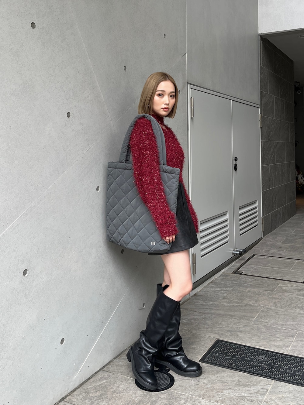 レッド系のニット/セーター、ブラウン系のスカート、ブラック系のブーツを着用したレディースの冬コーディネートの6枚目の写真