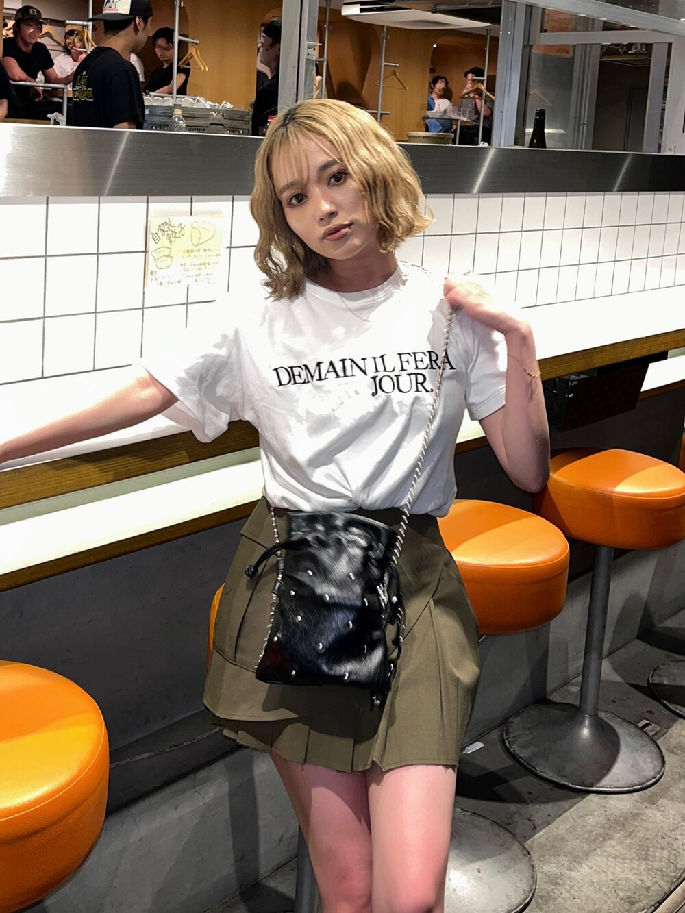 ブラック系のショルダーバッグ、グリーン系のスカートを着用したレディースの夏コーディネートの2枚目の写真